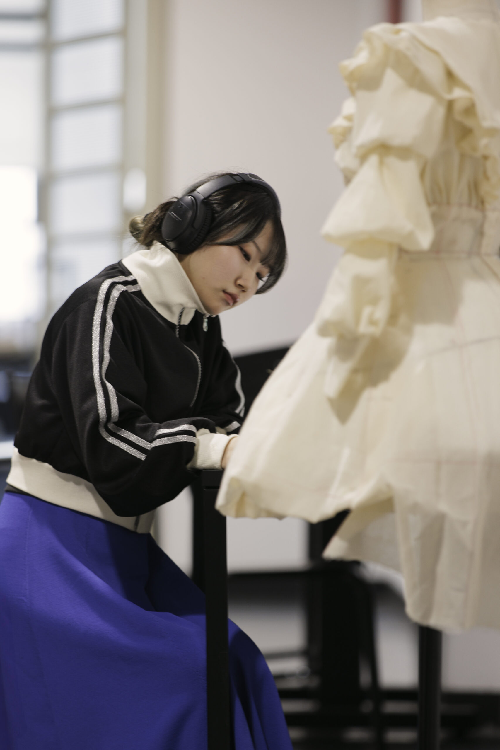 A girl working on her fashion designs in a university setting. Sustainable fashion topics can be integrated into all areas of business and design.