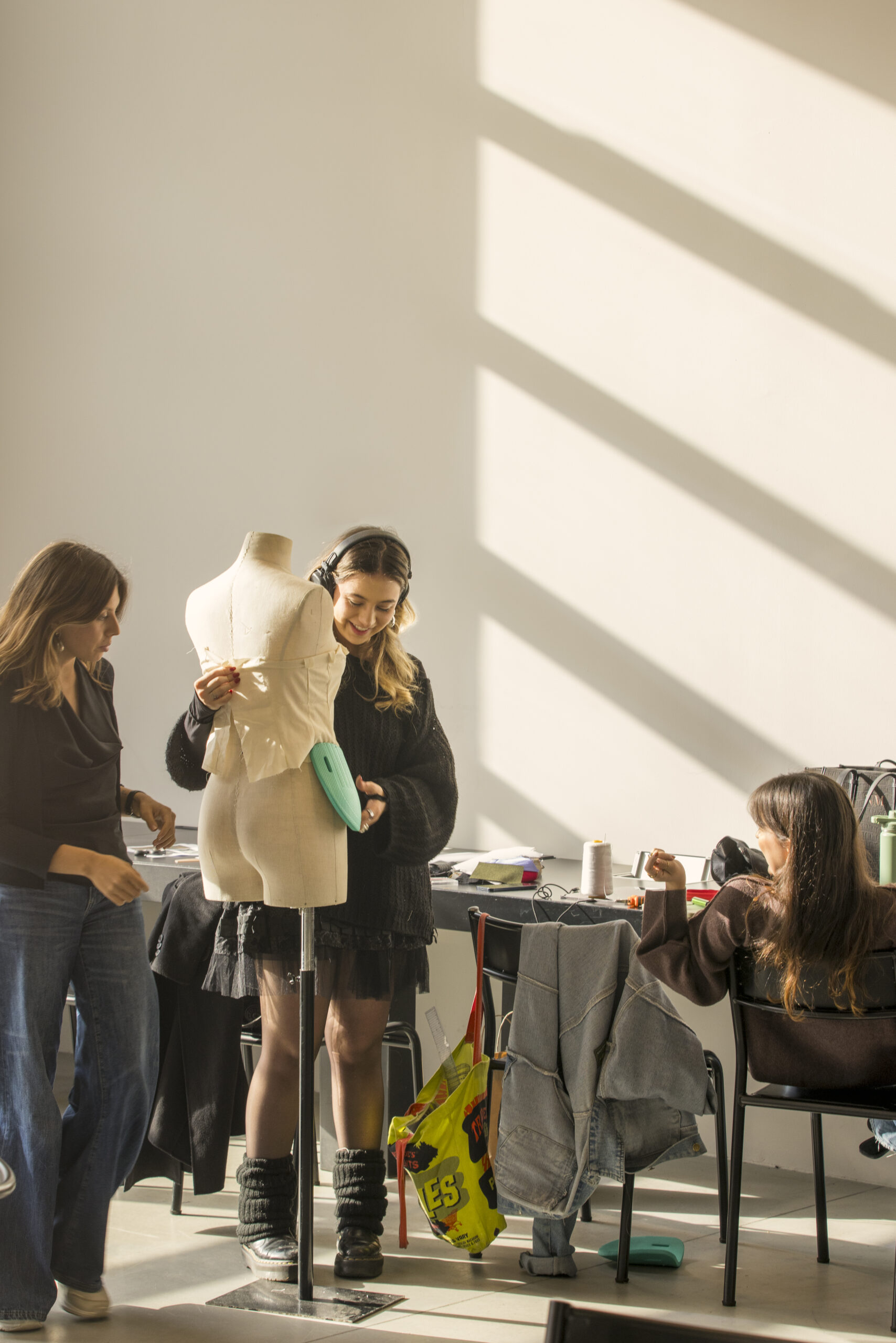 3 students work together around a mannequin on a sustainable fashion design.